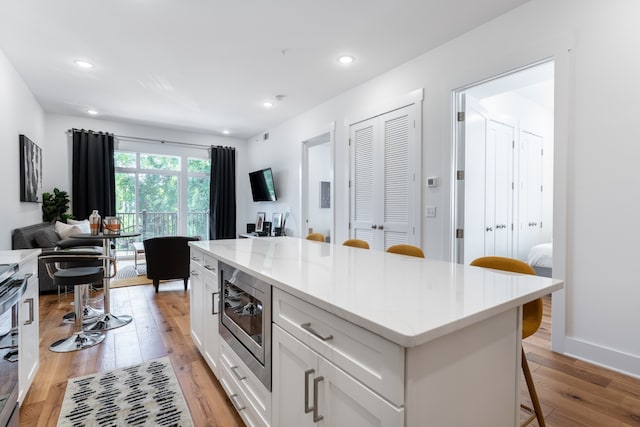 kitchen featuring appliances with stainless steel finishes, light hardwood / wood-style floors, white cabinetry, and a kitchen breakfast bar