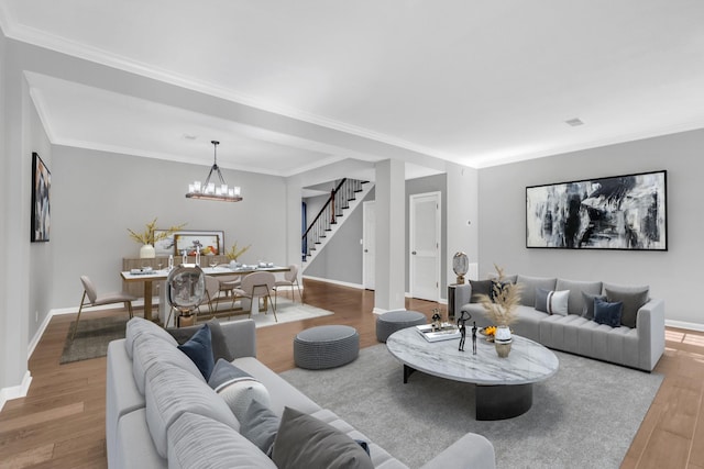 living room with an inviting chandelier, wood finished floors, crown molding, stairway, and baseboards