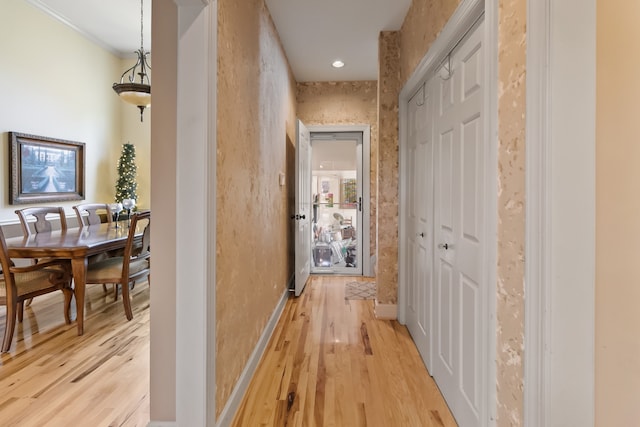 hall with light wood-type flooring and ornamental molding