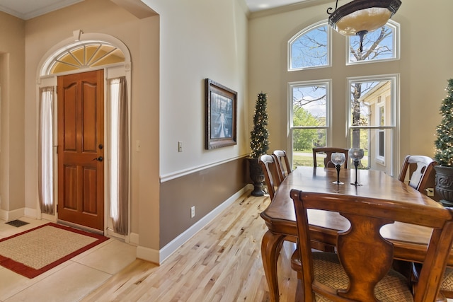 dining room featuring crown molding, light hardwood / wood-style floors, and a high ceiling