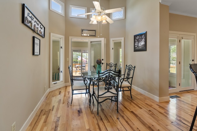 dining area with light hardwood / wood-style floors, a high ceiling, and a healthy amount of sunlight