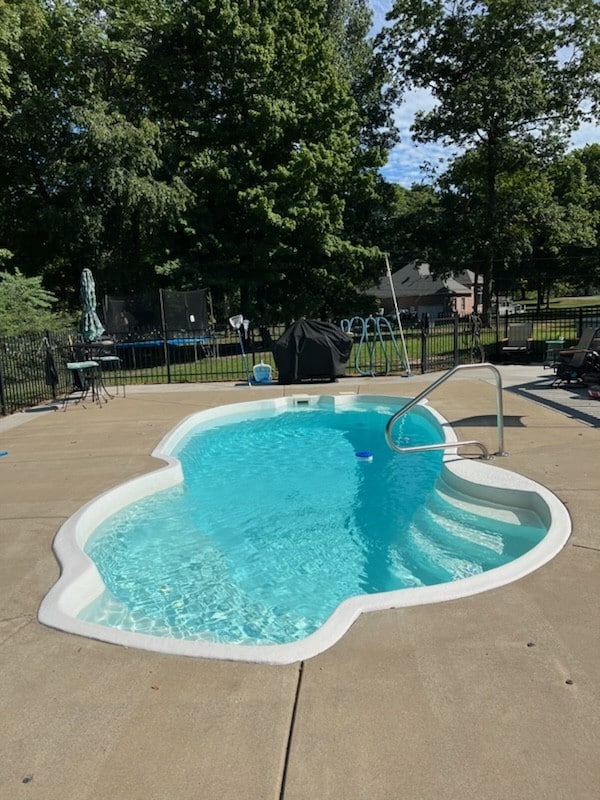 view of swimming pool with a patio area and a trampoline