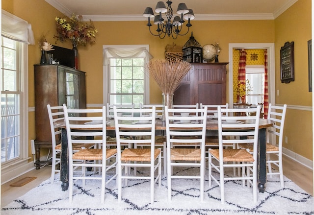 dining space featuring light wood-type flooring, a healthy amount of sunlight, and crown molding