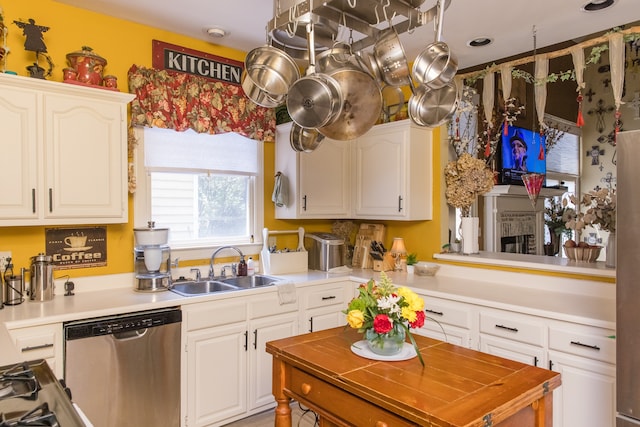 kitchen with a fireplace, white cabinets, sink, and stainless steel dishwasher