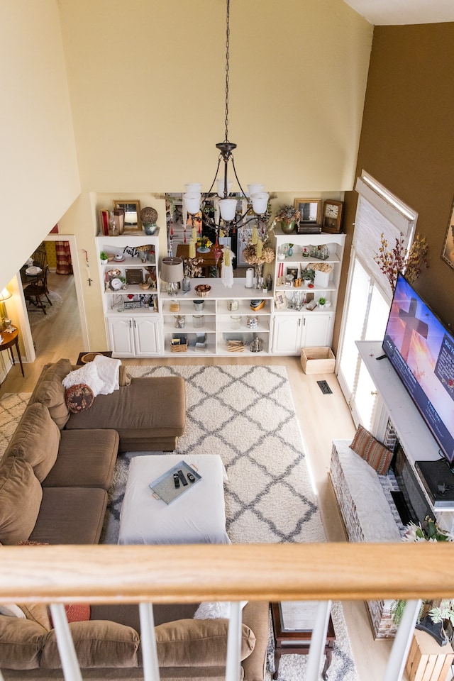 living room featuring an inviting chandelier, hardwood / wood-style floors, and a high ceiling