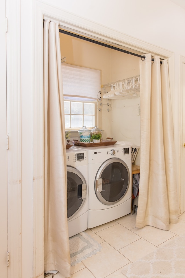 clothes washing area featuring light tile patterned flooring and washer and dryer