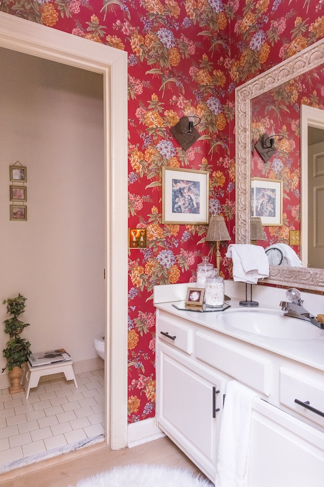 bathroom with toilet, vanity, and wood-type flooring