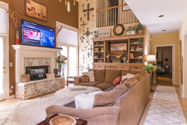 living room featuring a high ceiling, light wood-type flooring, and a fireplace