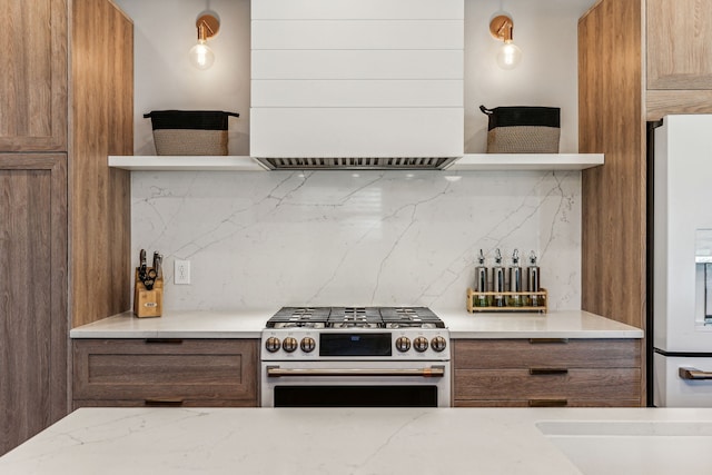 kitchen with decorative backsplash, light stone countertops, stainless steel stove, and white refrigerator with ice dispenser