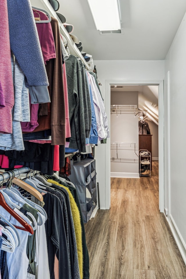 walk in closet with hardwood / wood-style floors and vaulted ceiling