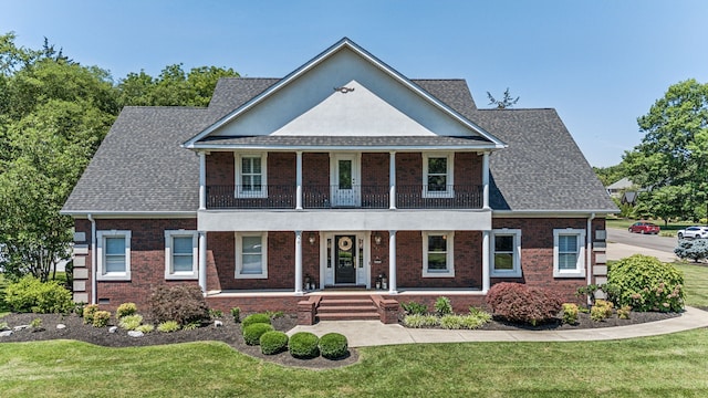 view of front of property featuring a front lawn, covered porch, and a balcony