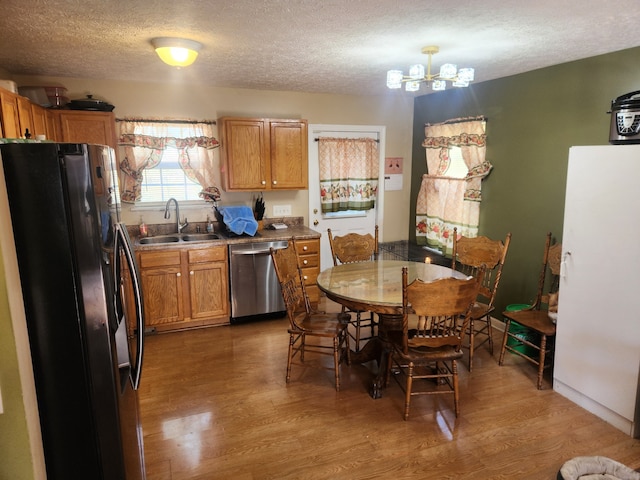 kitchen featuring appliances with stainless steel finishes, sink, a textured ceiling, dark hardwood / wood-style flooring, and a notable chandelier