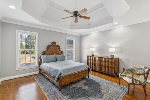 bedroom featuring ceiling fan, crown molding, a tray ceiling, and dark hardwood / wood-style floors