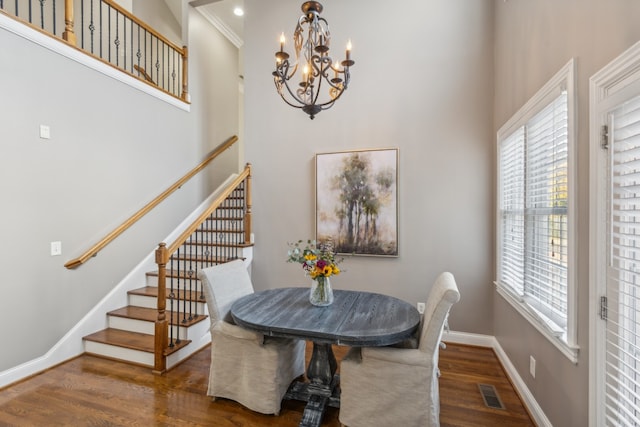 dining space with dark wood-type flooring, crown molding, and a chandelier