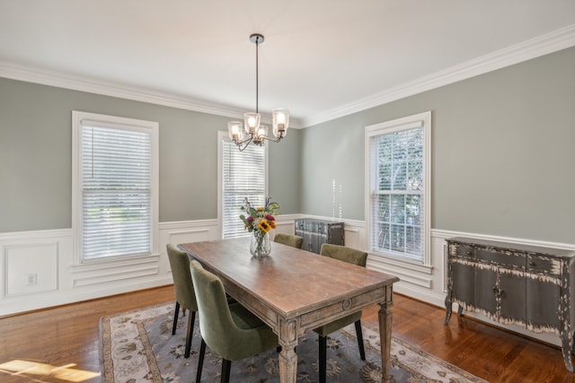 dining room featuring dark wood-type flooring, ornamental molding, a wealth of natural light, and an inviting chandelier