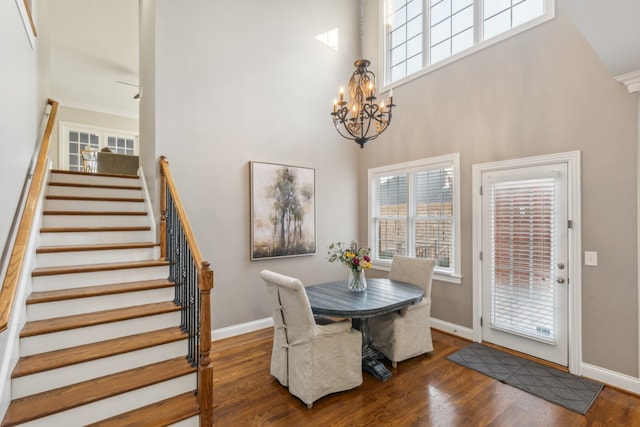 dining area featuring a towering ceiling, crown molding, a chandelier, and dark hardwood / wood-style flooring