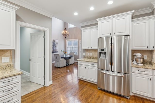 kitchen with white cabinetry, decorative backsplash, light wood-type flooring, and stainless steel fridge