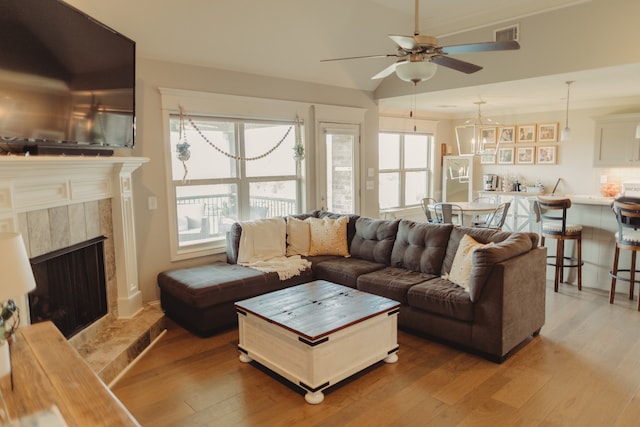 living room with a high end fireplace, wood-type flooring, and ceiling fan with notable chandelier