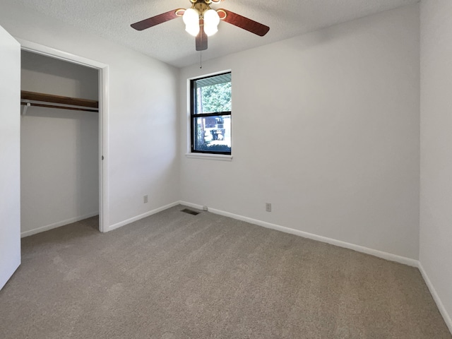 unfurnished bedroom featuring a closet, a textured ceiling, carpet flooring, and ceiling fan