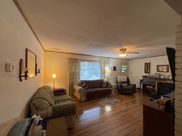 living room with a textured ceiling, crown molding, wood-type flooring, and ceiling fan