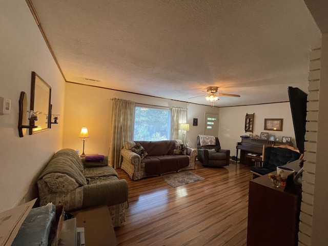 living room featuring ornamental molding, a textured ceiling, hardwood / wood-style flooring, and ceiling fan