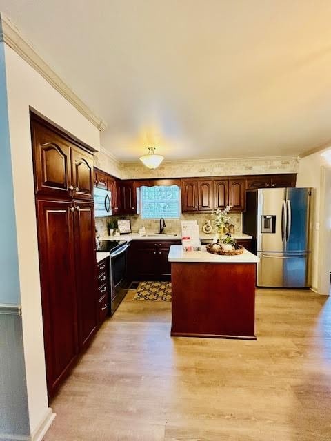 kitchen featuring light hardwood / wood-style floors, appliances with stainless steel finishes, a center island, and decorative backsplash