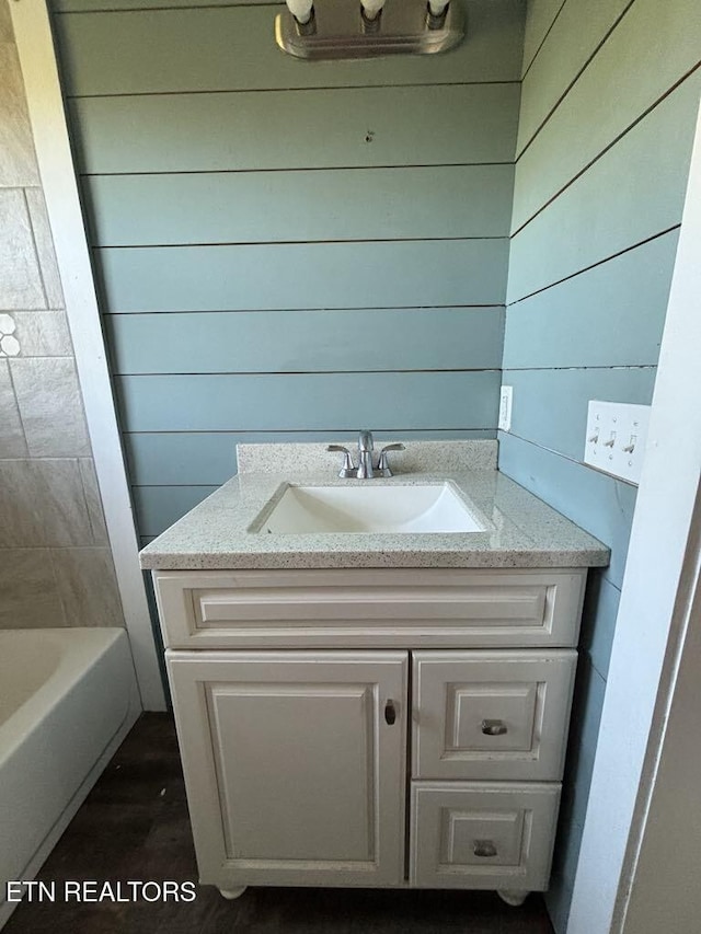 bathroom featuring vanity, wood walls, and a bathing tub