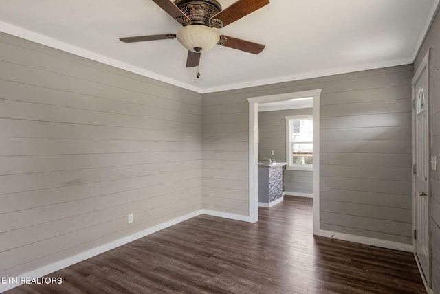 empty room featuring wood walls, dark hardwood / wood-style floors, and ceiling fan