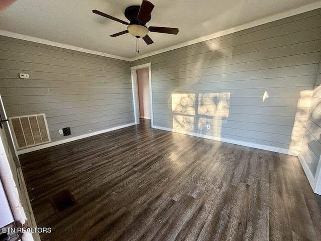 unfurnished room with ceiling fan, wood walls, and dark hardwood / wood-style floors