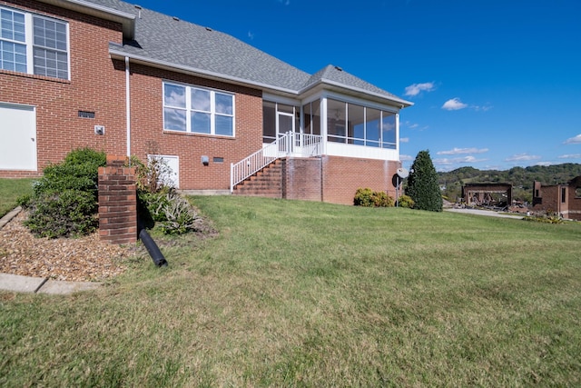 rear view of house featuring a sunroom and a lawn