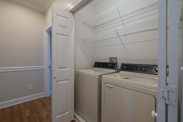 clothes washing area with washer and dryer, crown molding, and dark hardwood / wood-style flooring