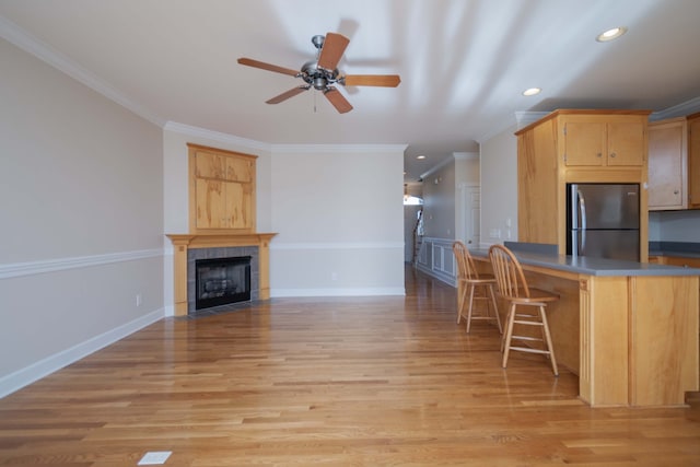 kitchen featuring light hardwood / wood-style floors, light brown cabinets, ornamental molding, and stainless steel refrigerator