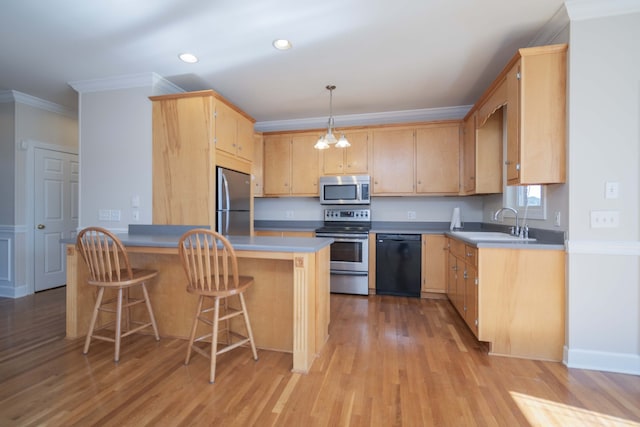 kitchen with appliances with stainless steel finishes, a breakfast bar, light brown cabinetry, light hardwood / wood-style floors, and decorative light fixtures