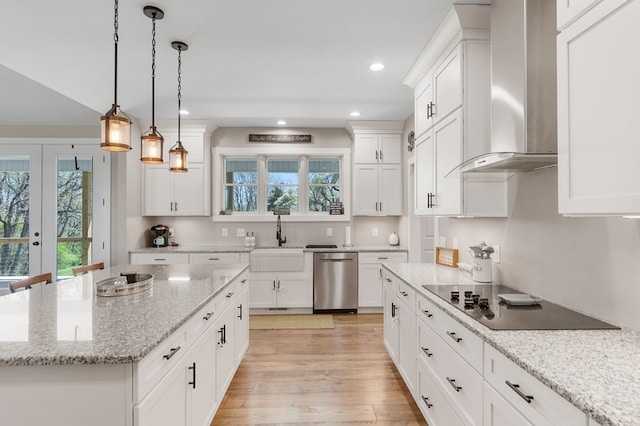 kitchen with decorative light fixtures, dishwasher, sink, black electric stovetop, and wall chimney exhaust hood