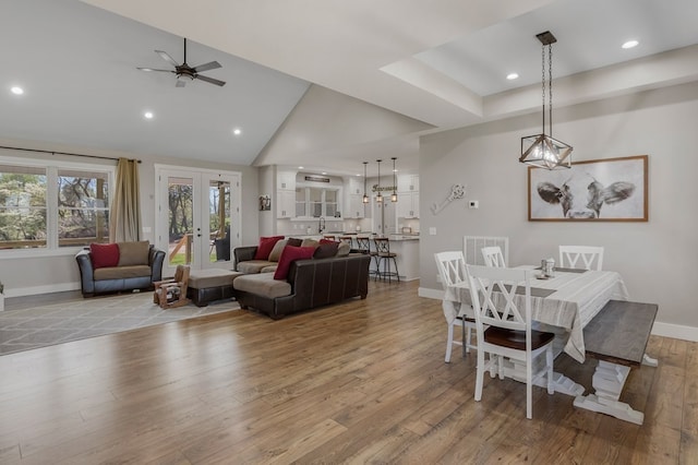 dining space with french doors, sink, vaulted ceiling, light wood-type flooring, and ceiling fan