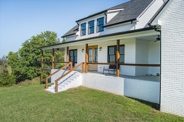 view of front of property featuring ceiling fan, a front yard, and covered porch