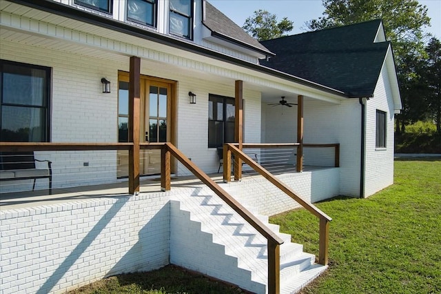 property entrance with ceiling fan, a porch, and a lawn