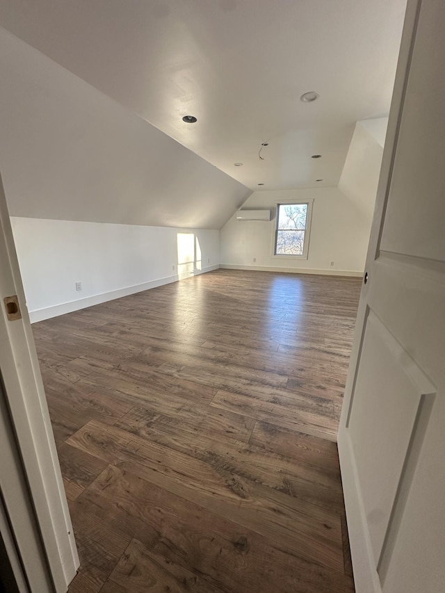 bonus room featuring dark wood-type flooring, lofted ceiling, and a wall mounted air conditioner