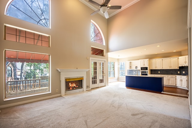 unfurnished living room with a wealth of natural light, a high ceiling, light carpet, and crown molding