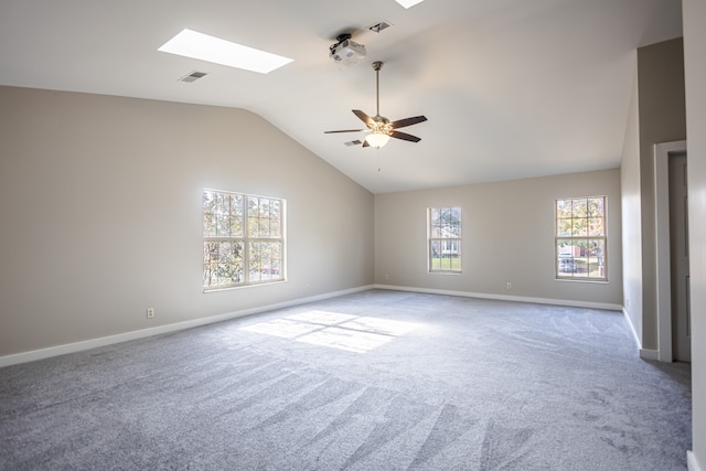 carpeted empty room featuring ceiling fan and vaulted ceiling with skylight