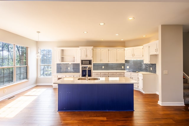 kitchen with dark hardwood / wood-style flooring, white cabinetry, a kitchen island with sink, and appliances with stainless steel finishes