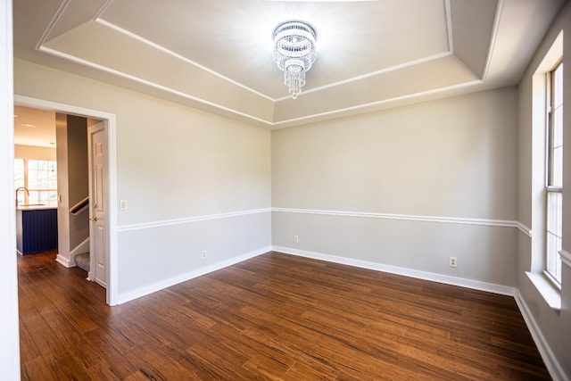 unfurnished room with a chandelier, dark hardwood / wood-style floors, a raised ceiling, and sink