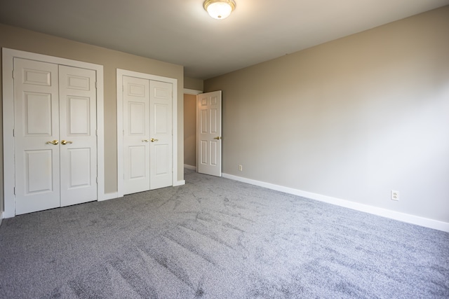 unfurnished bedroom featuring two closets and carpet floors