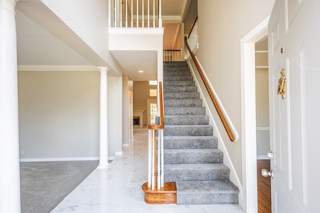 stairs featuring decorative columns, ornamental molding, and carpet floors