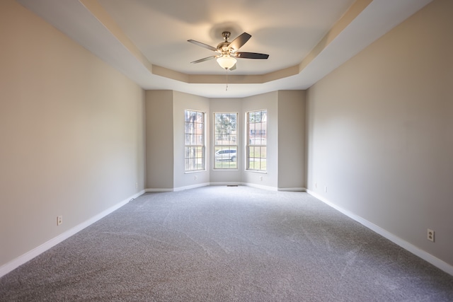 unfurnished room featuring ceiling fan, carpet flooring, and a tray ceiling