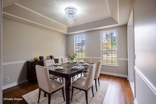 dining room with dark hardwood / wood-style flooring, a tray ceiling, and a notable chandelier