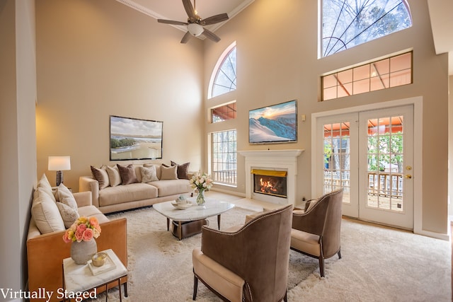 carpeted living room with a high ceiling, ceiling fan, and ornamental molding