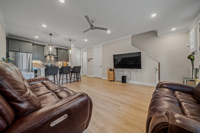 living room with light wood-type flooring, ceiling fan, and crown molding