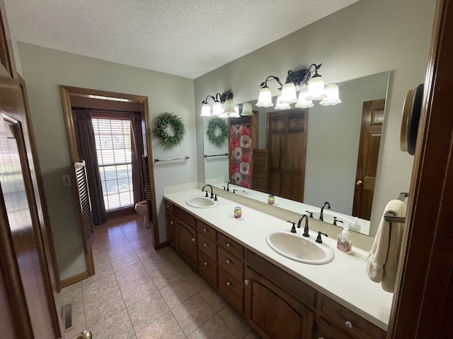 bathroom featuring vanity, toilet, tile patterned floors, and a textured ceiling