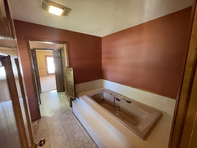 bathroom with a textured ceiling, a washtub, and tile patterned flooring